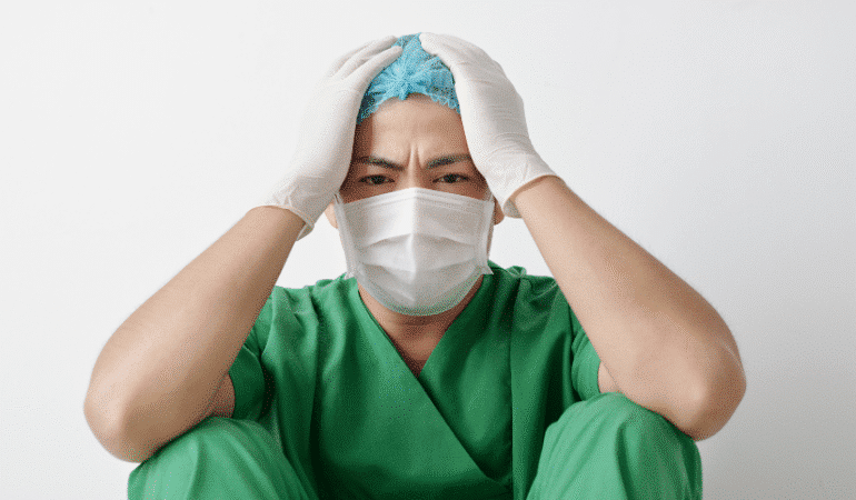 başını ellerinin arasına almış sağlık çalışanı